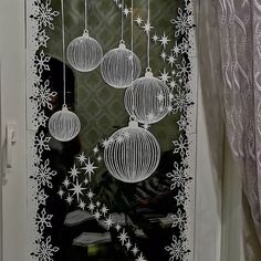 the window is decorated with christmas ornaments and snowflakes hanging from it's sides