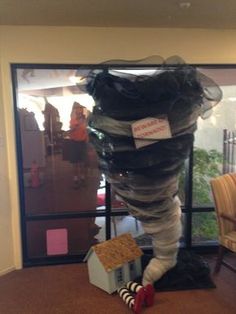 a house made out of plastic wrapped in black and white material, sitting on the floor next to a window