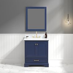 a bathroom vanity with a blue cabinet and mirror on the wall next to a light fixture