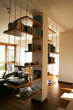 a living room filled with furniture and bookshelves next to a large open window