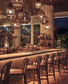 a bar with chairs and lights hanging from the ceiling