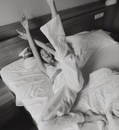 a woman laying in bed with her arms up