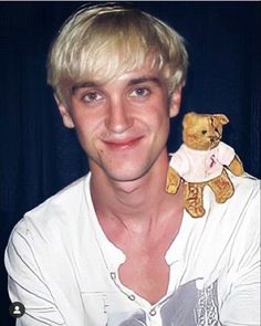 a man with blonde hair holding a teddy bear