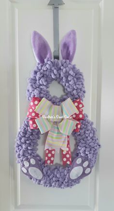 a purple bunny wreath with polka dots and a bow hanging on the front door handle