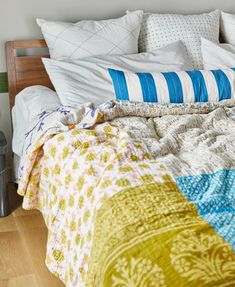 an unmade bed with white and blue pillows