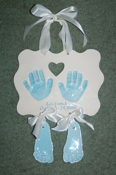 two blue handprints and one white heart hang from a ribbon on the floor