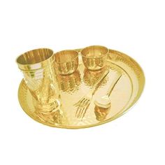 a gold plate with four cups and two spoons