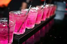 pink drinks lined up on a black tray