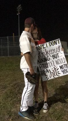 a man and woman standing next to each other holding a sign that says i hope i don't