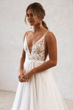 a woman wearing a white wedding dress with straps