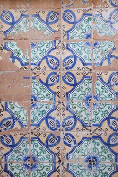 an old tile wall with blue and green designs