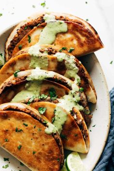 several pita breads on a white plate topped with green sauce and cilantro