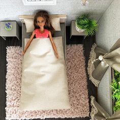 a doll is laying on a bed in the middle of a room with pink carpet