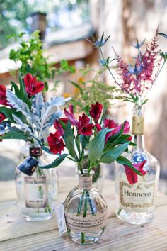 three bottles with flowers in them sitting on a table