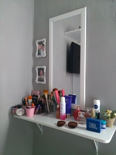 a white table topped with lots of makeup and personal care items next to a mirror