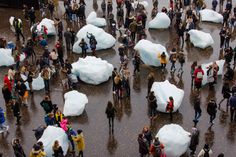 a crowd of people standing around giant icebergs on a wet street in front of a building