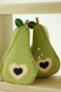 two green pears sitting on top of a wooden shelf next to each other, one with a heart in the middle