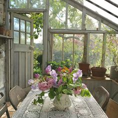 a vase filled with flowers sitting on top of a table in front of a window