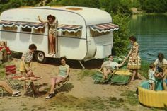 a group of people sitting in lawn chairs next to an old camper with a woman standing on top