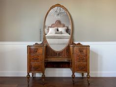 a bedroom with a large mirror on the wall and a dresser in front of it