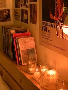 candles are lit on a shelf in front of a poster