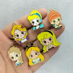 the little princesses are in different colors and designs on this keychain, which is being held by someone's hand