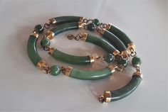 Vintage carved green jade and gold plate elements link station necklace with long carved jade curved tube beads with gold plate ends and ball beads spacers with gold metal flower caps on each side - with clasp. Note that the beads are linked with brass tone metal rings. Matching bracelets are listed separately. 22 inches end to end; curved jade tubes: 1.5 x 1/4 inches; ball beads: 3/8 inches. Good condition with imperfection expected from a hard carved piece as shown - sold as is.  To make this Rings Matching, Carved Jade, Metal Flower, Ball Necklace, Chinese Characters, Jade Carving, Station Necklace, Jade Jewelry, Necklace Choker