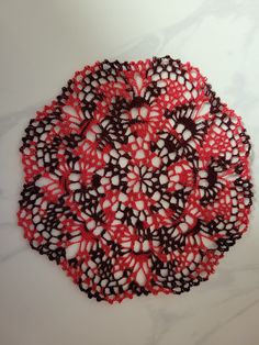 a crocheted doily is shown on a marble surface