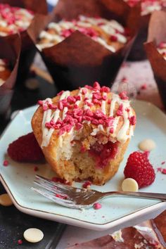 a muffin on a plate with raspberries and white chocolate