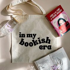 an open book, water bottle and tote bag with the words in my bookish era printed on it