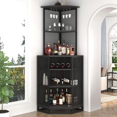 a black shelf with bottles and glasses on it next to a potted plant in a living room