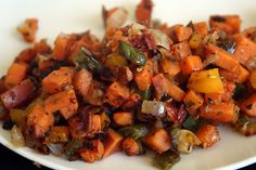 a white plate topped with cooked vegetables on top of a table