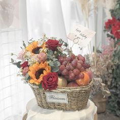 a basket filled with lots of different types of fruits and flowers on top of a table