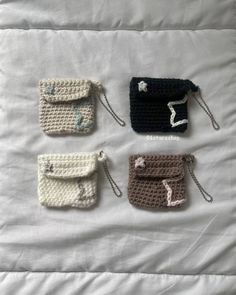 four small crocheted purses on a bed