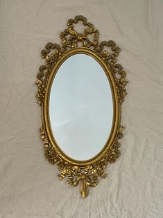 an ornate gold framed mirror on a white sheet