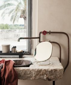 a bathroom sink sitting next to a window with a towel hanging on the side of it