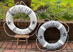 two life preservers sitting next to each other on a brick walkway in front of a flower garden