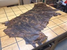 a piece of leather sitting on top of a wooden table next to a tile floor