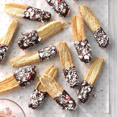 chocolate covered candy canes are arranged on a sheet of paper with sprinkles