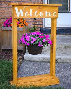 a welcome sign with potted flowers hanging from it