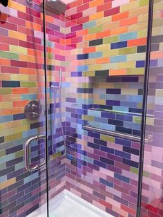 a colorful tiled shower with glass doors and no tub in the corner, it looks like something out of space