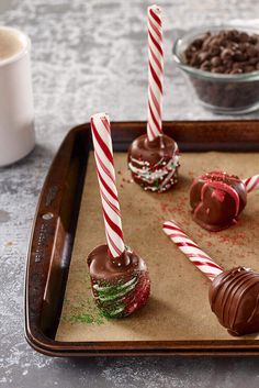 three chocolate covered desserts on a tray with candy canes