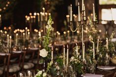 a long table with candles and flowers on it is set for a formal dinner or reception