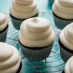 cupcakes with white frosting sitting on a cooling rack