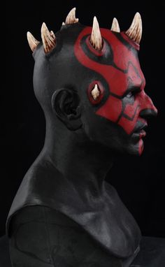 a black and red mask with spikes on it's head is shown in front of a black background