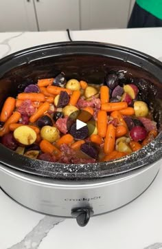 a slow cooker filled with carrots, potatoes and other vegetables on a counter