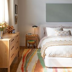 a bedroom with a bed, dresser and lamp