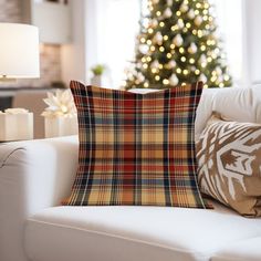 a living room with a christmas tree in the background and plaid pillows on the couch