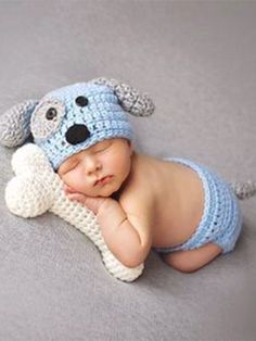 a baby wearing a crochet dog hat and diaper is laying on the floor