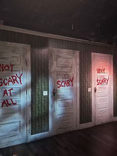 three wooden doors with red spray paint on them and the words not scary at all written on them